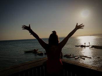 Silhouette woman standing by sea against sky during sunset