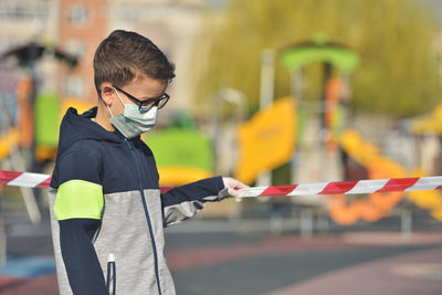 Close-up of boy wearing mask standing outdoors