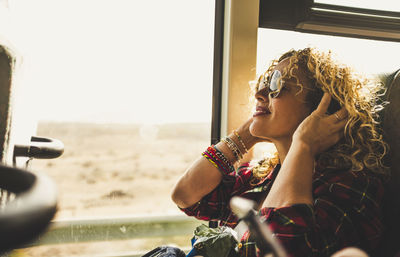 Portrait of young woman looking through window