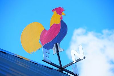 Low angle view of weather vane against blue sky