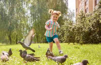 Cute girl playing on grass with birds