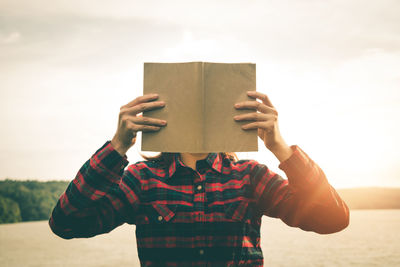 Man reading book while sitting outdoors