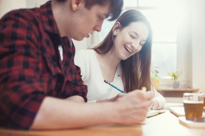 Young woman using phone while sitting on table