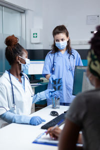 Doctor and nurse wearing mask having discussion at hospital