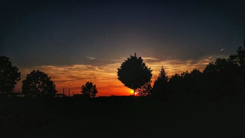 Silhouette trees on landscape against sunset sky