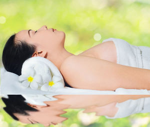 Side view of woman lying on green blurred background