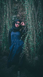 Portrait of young woman standing on field in forest