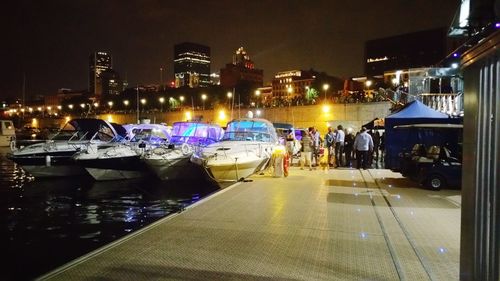 Boats moored in illuminated city at night