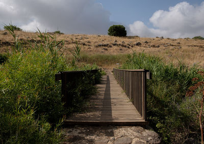 Boardwalk on field against sky