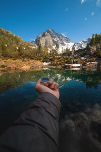 A man with a compass in his hand in the high mountains against the backdrop of a clear lake. travel