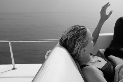 Woman resting on boat while sailing in sea