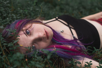 Portrait of young woman lying on plants
