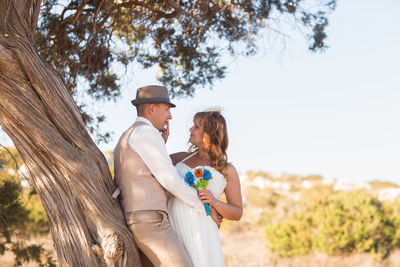 Side view of couple standing against trees