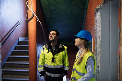 Female and male managers discussing while standing by steps at construction site