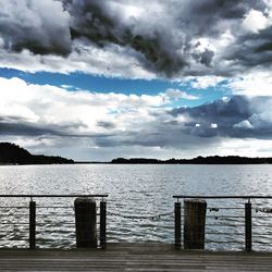 Pier on lake against cloudy sky