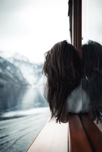 Rear view of woman leaning from boat window