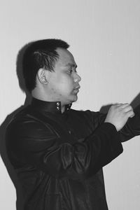 Side view of young man looking away against white background