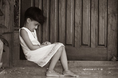 Side view of teenage girl sitting against wall