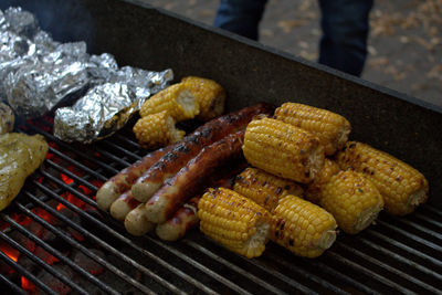 High angle view of sweetcorns and sausages on barbecue grill