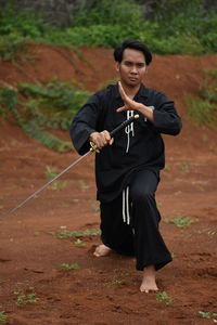 Portrait of young man with sword practicing on field