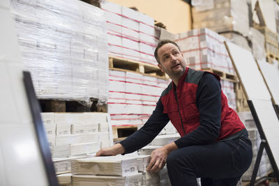 Salesman looking away while arranging packages in hardware store