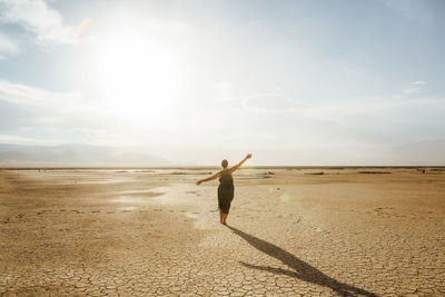 Woman standing in desert against sky