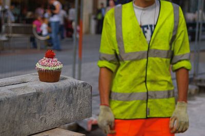 Cupcake on retaining wall with worker in background