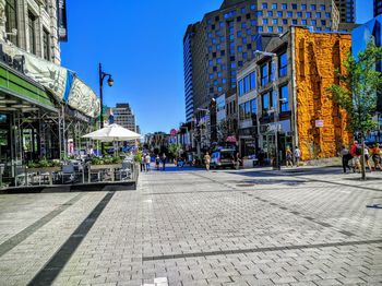 City street by buildings against clear blue sky