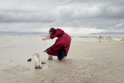 Rear view of woman standing at beach against sky