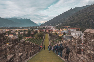 Group of people on mountain against cloudy sky