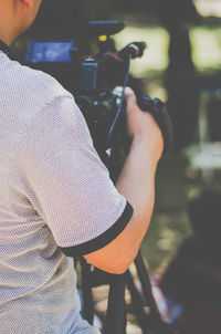 Midsection of man operating television camera