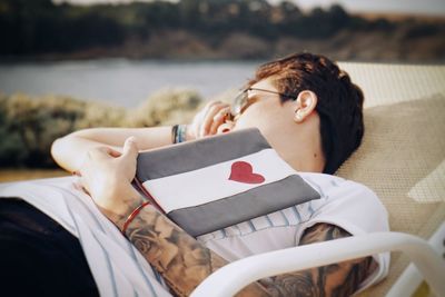 Woman holding book lying on lounge chair