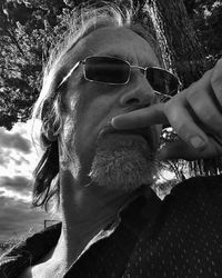 Close-up portrait of young man smoking on sunglasses