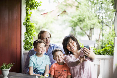 Mother taking selfie with family in porch