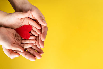 Close-up of man holding yellow hands against gray background