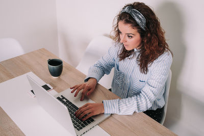 Young woman using mobile phone while sitting on table