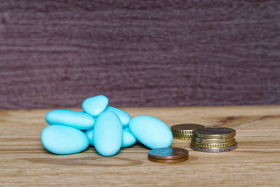 Close-up of blue medicines and coins on wooden table