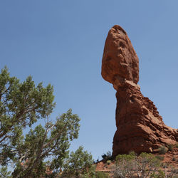 Low angle view of rock formation against clear blue sky