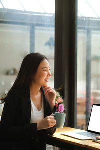 Young woman drinking coffee while sitting on table