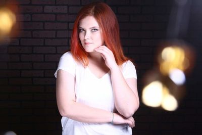 Portrait of beautiful woman standing against brick wall