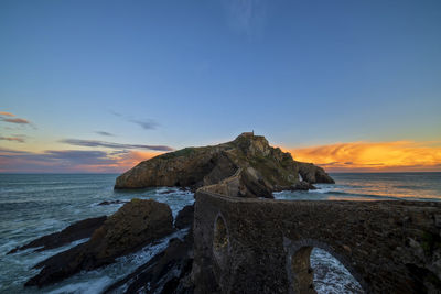 Scenic view of rocks on beach against sky during sunset