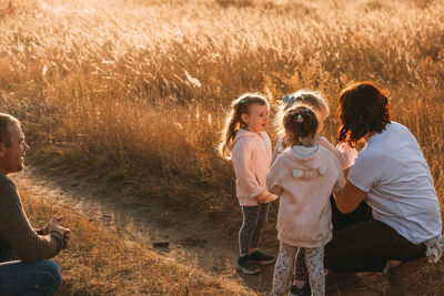 Family on a walk. happy father watches his triplet daughters play with mom outdoors