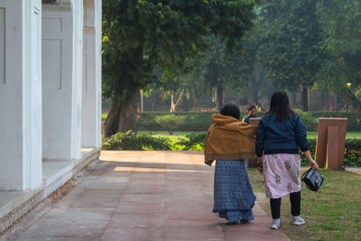 Rear view of women with umbrella against trees