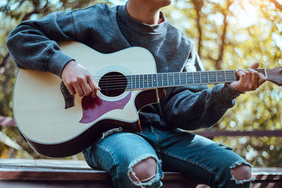 Midsection of man playing guitar