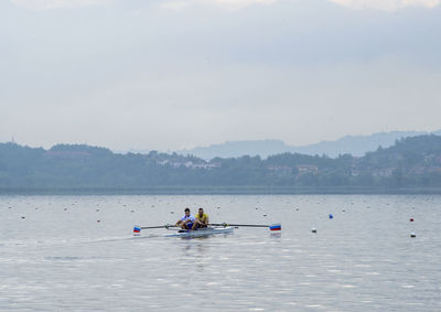 People on boat in sea against sky