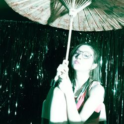 Young woman holding umbrella at night