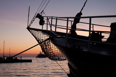 Silhouette sailboat on sea against orange sky