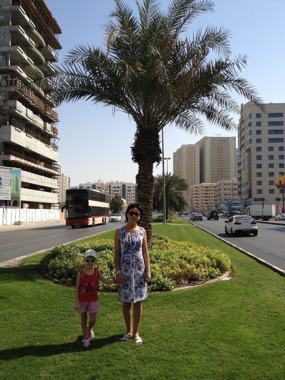 REAR VIEW OF A BOY STANDING BY TREE IN CITY