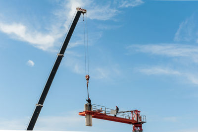 Low angle view of crane at construction site against sky