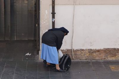 Rear view of woman standing against wall